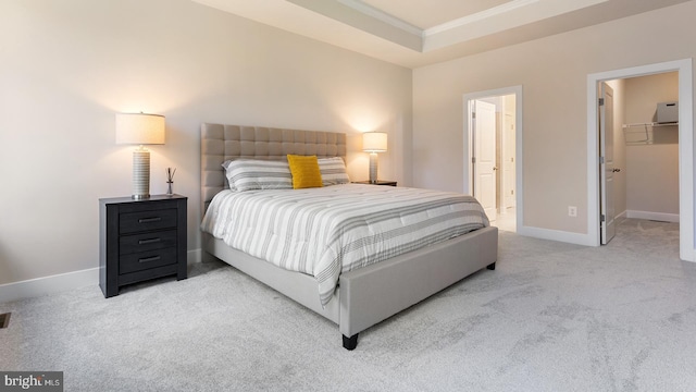 carpeted bedroom with a raised ceiling, a walk in closet, crown molding, and a closet