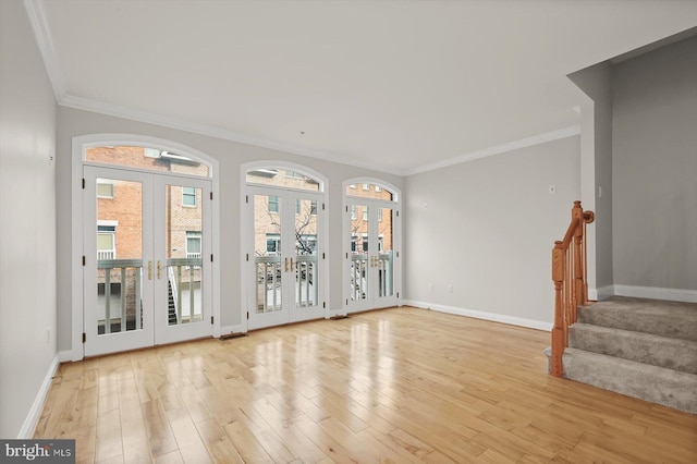 unfurnished living room featuring a healthy amount of sunlight, crown molding, light hardwood / wood-style flooring, and french doors