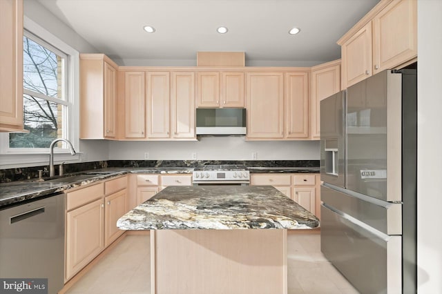 kitchen featuring dark stone counters, stainless steel appliances, sink, light tile patterned floors, and a center island