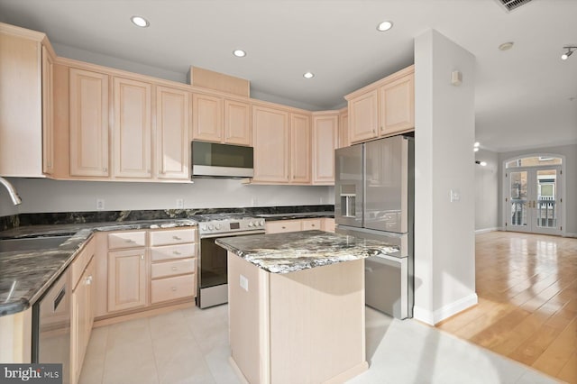 kitchen featuring dark stone counters, french doors, sink, light hardwood / wood-style flooring, and appliances with stainless steel finishes