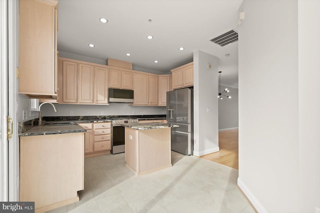 kitchen with dark stone counters, sink, light brown cabinetry, a kitchen island, and stainless steel appliances