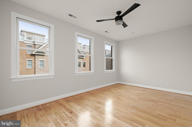 spare room with ceiling fan, light wood-type flooring, and a wealth of natural light