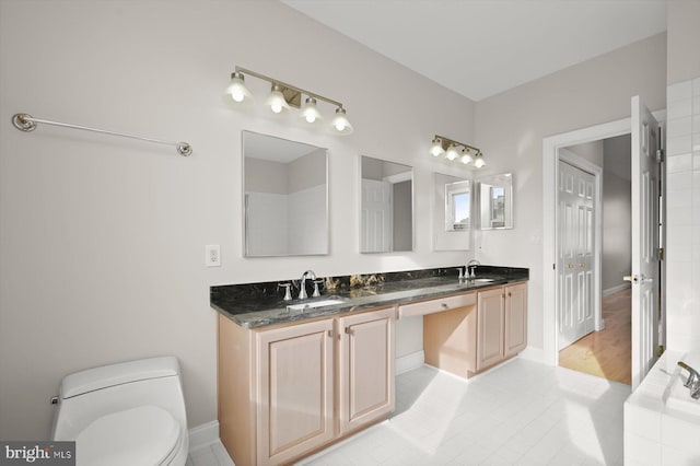 bathroom featuring tile patterned flooring, a bath, vanity, and toilet