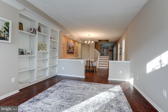 interior space with built in shelves, dark hardwood / wood-style flooring, a textured ceiling, and a notable chandelier