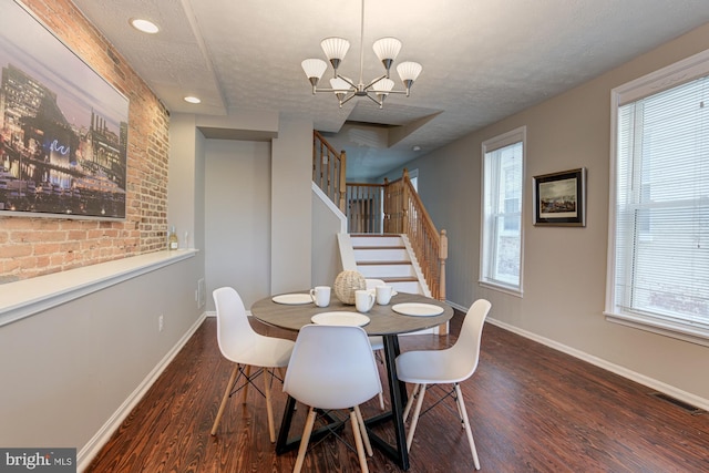 dining area with a textured ceiling, dark hardwood / wood-style floors, and an inviting chandelier