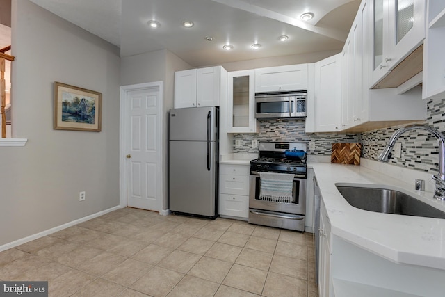 kitchen featuring appliances with stainless steel finishes, backsplash, sink, white cabinets, and light tile patterned flooring