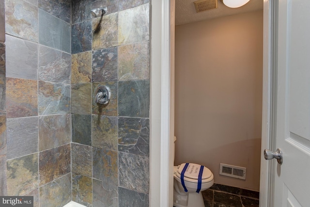 bathroom featuring tiled shower and toilet