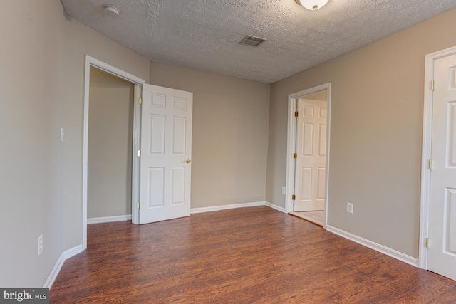 spare room featuring dark hardwood / wood-style floors and a textured ceiling