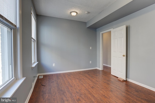 unfurnished room featuring dark wood-type flooring and a textured ceiling