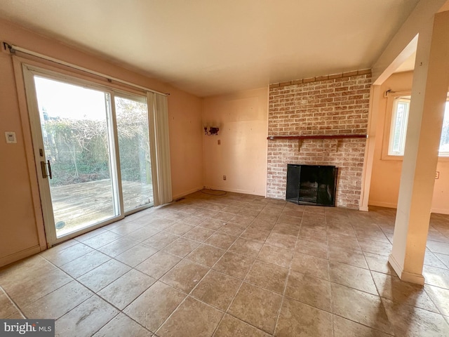 unfurnished living room with a fireplace, light tile patterned floors, and a wealth of natural light