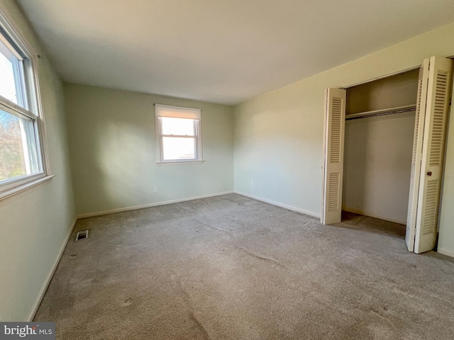 unfurnished bedroom featuring a closet and light colored carpet