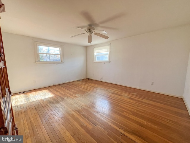 empty room with ceiling fan, a healthy amount of sunlight, and wood-type flooring