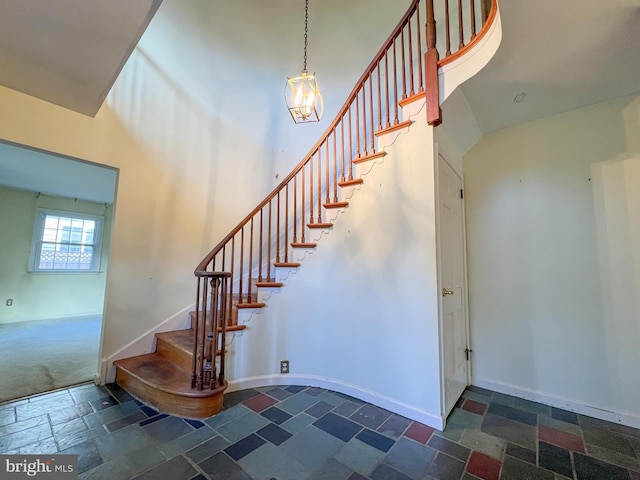 staircase featuring a high ceiling and an inviting chandelier