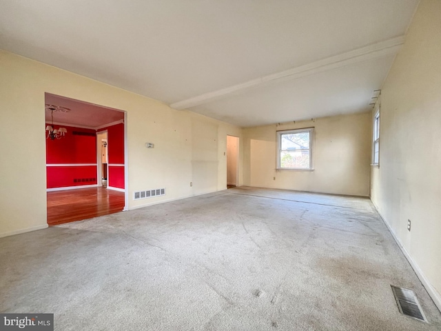 carpeted spare room featuring a notable chandelier