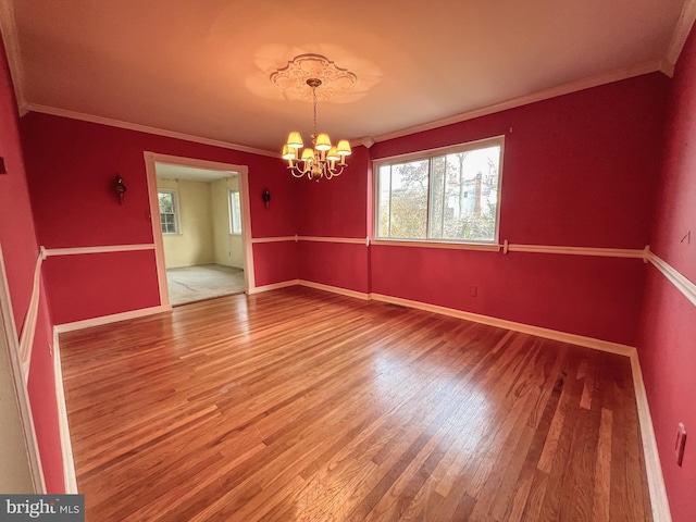 unfurnished dining area featuring hardwood / wood-style floors, ornamental molding, and an inviting chandelier