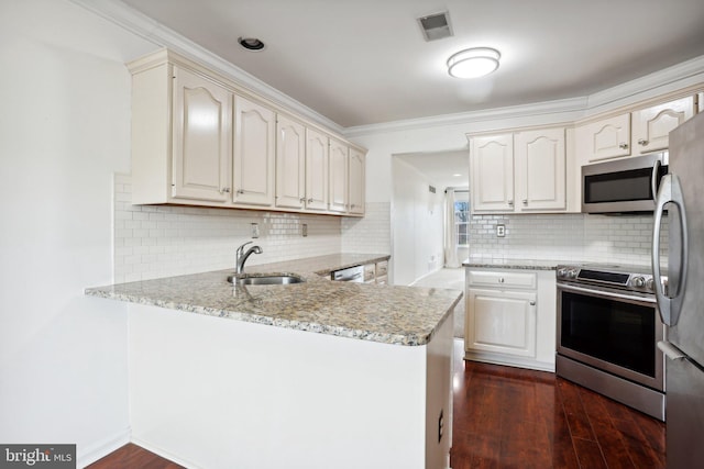 kitchen with light stone countertops, sink, dark hardwood / wood-style flooring, kitchen peninsula, and appliances with stainless steel finishes