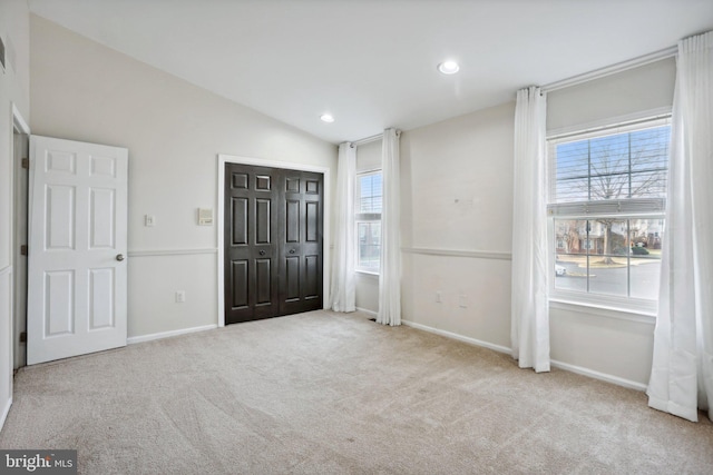 unfurnished bedroom featuring lofted ceiling, light carpet, and a closet