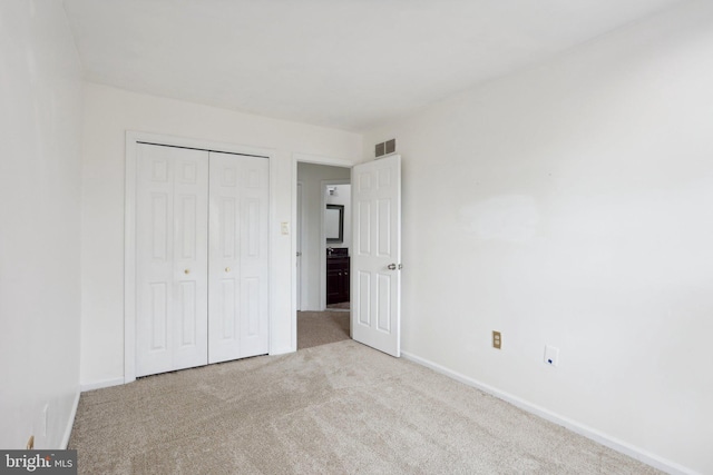 unfurnished bedroom with light carpet and a closet