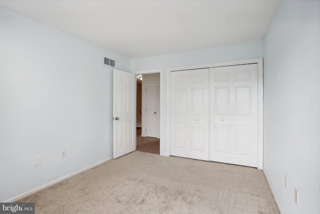 unfurnished bedroom with light carpet and a closet