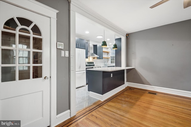 interior space with wall chimney exhaust hood, stainless steel range, blue cabinetry, white refrigerator, and light hardwood / wood-style floors