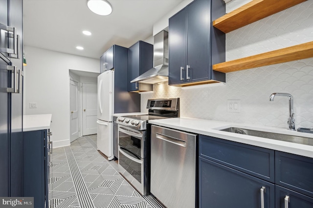 kitchen featuring backsplash, wall chimney range hood, sink, blue cabinetry, and appliances with stainless steel finishes