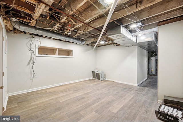 basement with water heater and hardwood / wood-style flooring