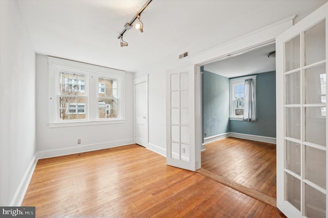 unfurnished room with lofted ceiling, light hardwood / wood-style floors, french doors, and track lighting