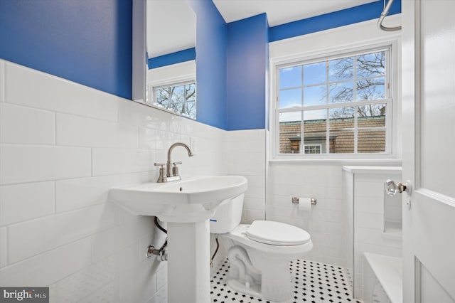 bathroom featuring tile patterned flooring, toilet, and tile walls