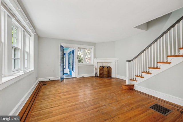 unfurnished living room featuring light hardwood / wood-style floors, a brick fireplace, and plenty of natural light