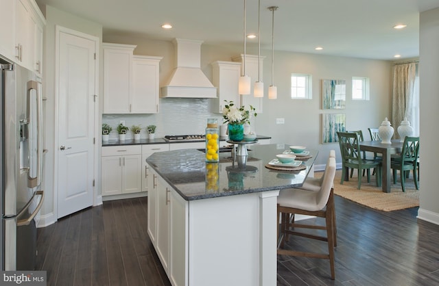 kitchen featuring a center island, custom range hood, appliances with stainless steel finishes, dark hardwood / wood-style flooring, and white cabinetry