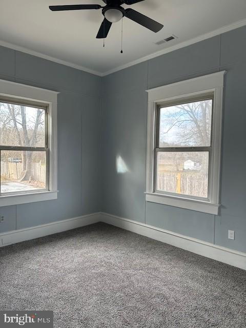 empty room with a wealth of natural light, crown molding, and carpet floors