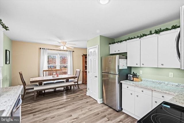 kitchen featuring ceiling fan, light stone counters, light hardwood / wood-style floors, white cabinets, and appliances with stainless steel finishes