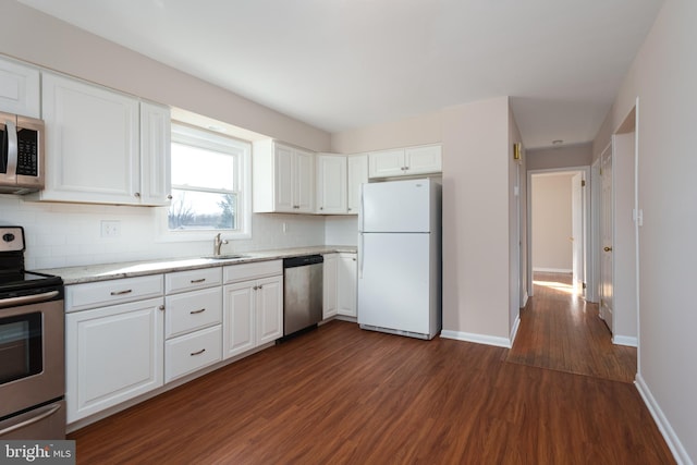 kitchen with sink, tasteful backsplash, dark hardwood / wood-style floors, white cabinets, and appliances with stainless steel finishes