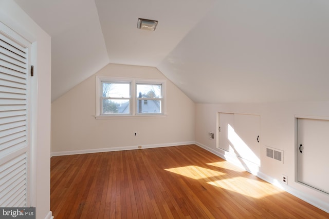 additional living space with hardwood / wood-style flooring and lofted ceiling