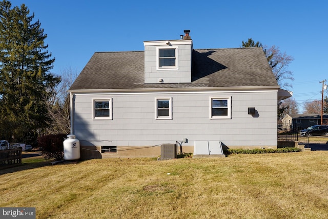 back of property with central air condition unit and a yard