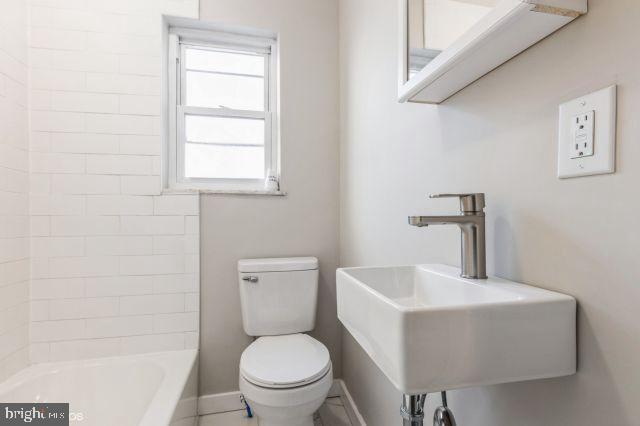 bathroom featuring toilet, a tub, and sink