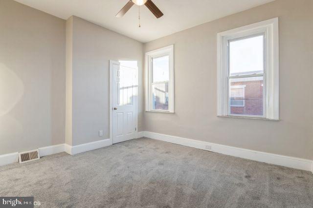 spare room featuring ceiling fan, light carpet, and a wealth of natural light