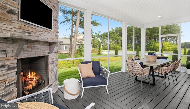 sunroom with plenty of natural light and an outdoor stone fireplace