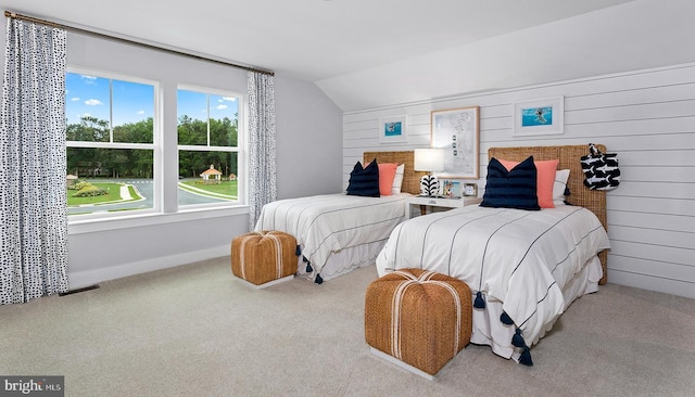 carpeted bedroom featuring lofted ceiling and wood walls