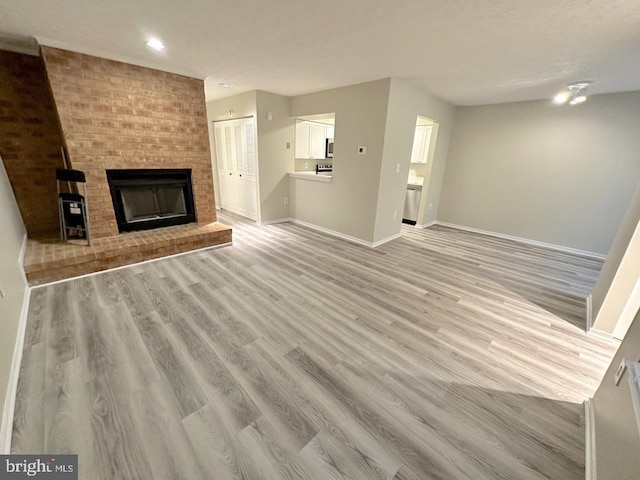 unfurnished living room featuring a brick fireplace and light hardwood / wood-style flooring