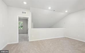 additional living space with light colored carpet and vaulted ceiling