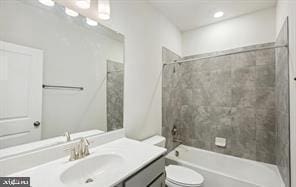 full bathroom featuring tiled shower / bath combo, toilet, and vanity