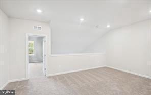 carpeted empty room featuring vaulted ceiling