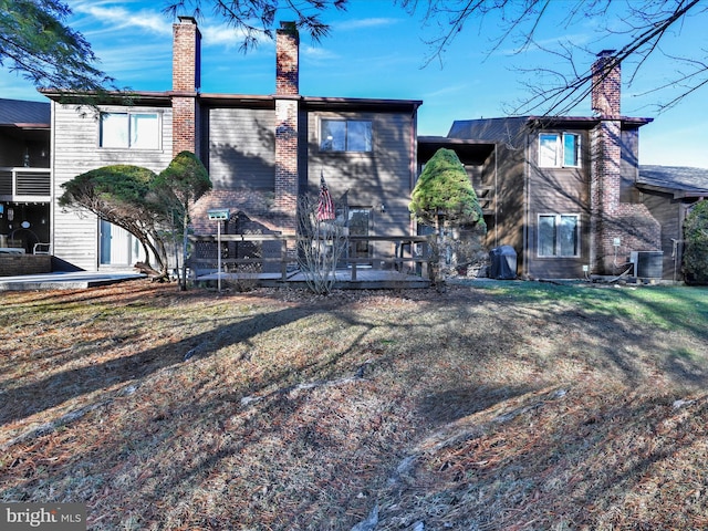 back of property featuring central air condition unit and a lawn