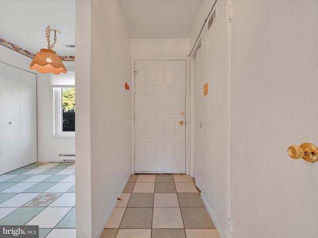 corridor with light tile patterned floors and a baseboard heating unit