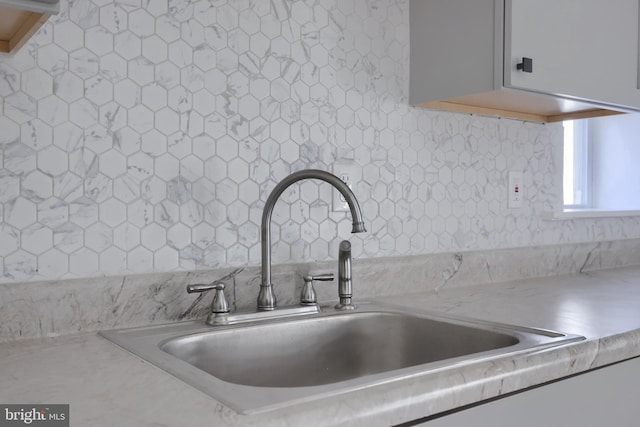 details featuring tasteful backsplash and sink