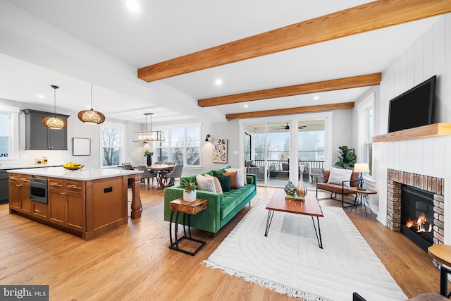 living room featuring beam ceiling, a fireplace, and light wood-type flooring