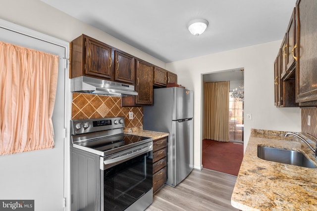 kitchen featuring sink, tasteful backsplash, stainless steel appliances, light stone countertops, and light hardwood / wood-style floors