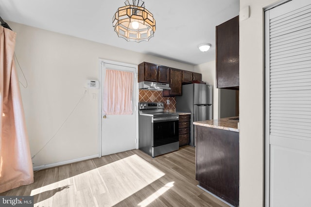 kitchen with backsplash, light stone counters, dark brown cabinetry, stainless steel appliances, and light hardwood / wood-style floors