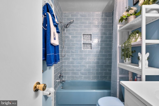 full bathroom featuring vanity, tiled shower / bath combo, and toilet